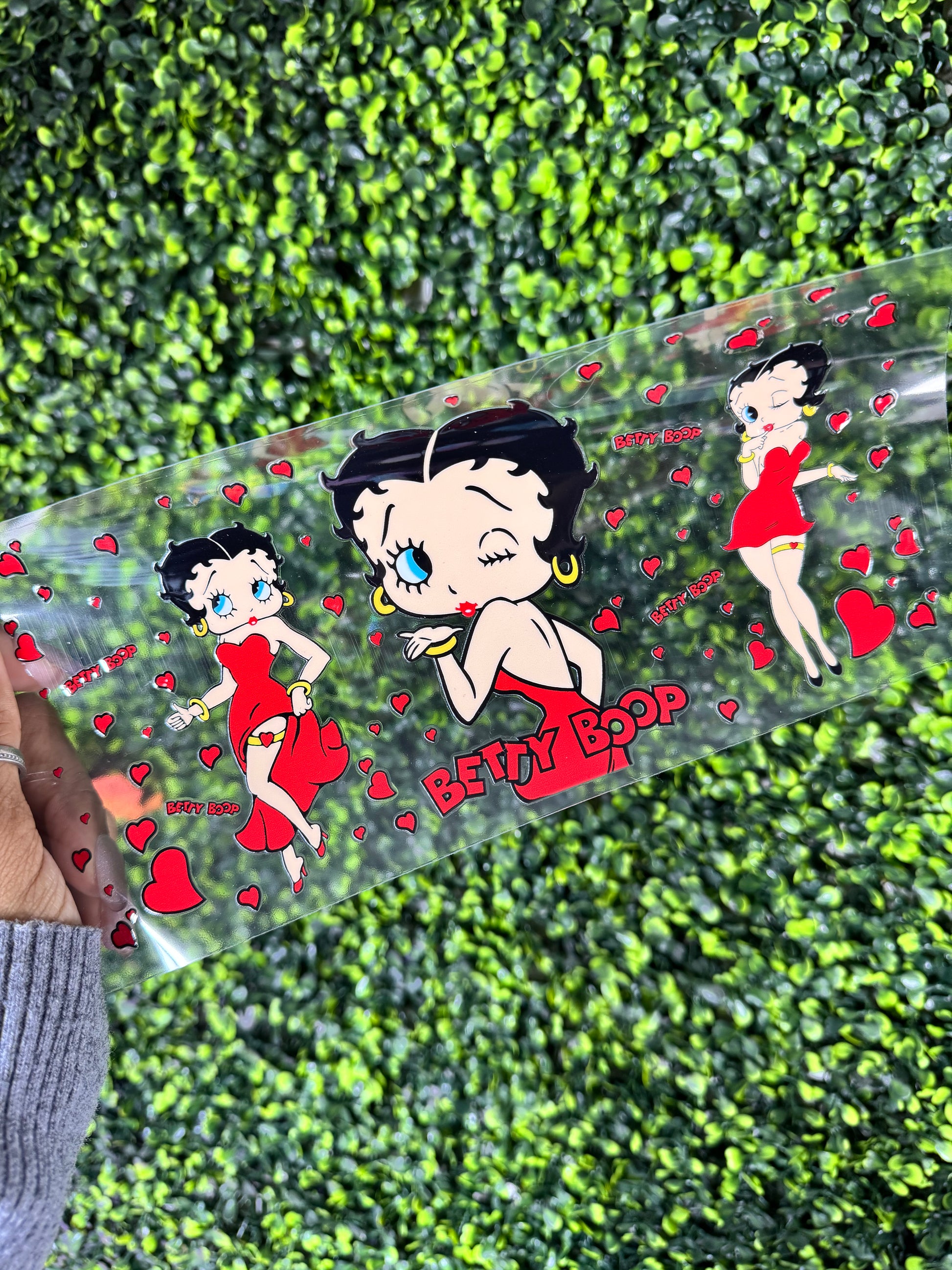 Clear plastic sheet with Betty Boop designs on a green leafy background